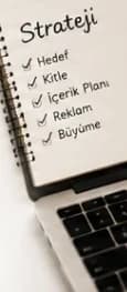 Hedef kitle ve reklam planı yazılı açık defter ve dizüstü bilgisayar